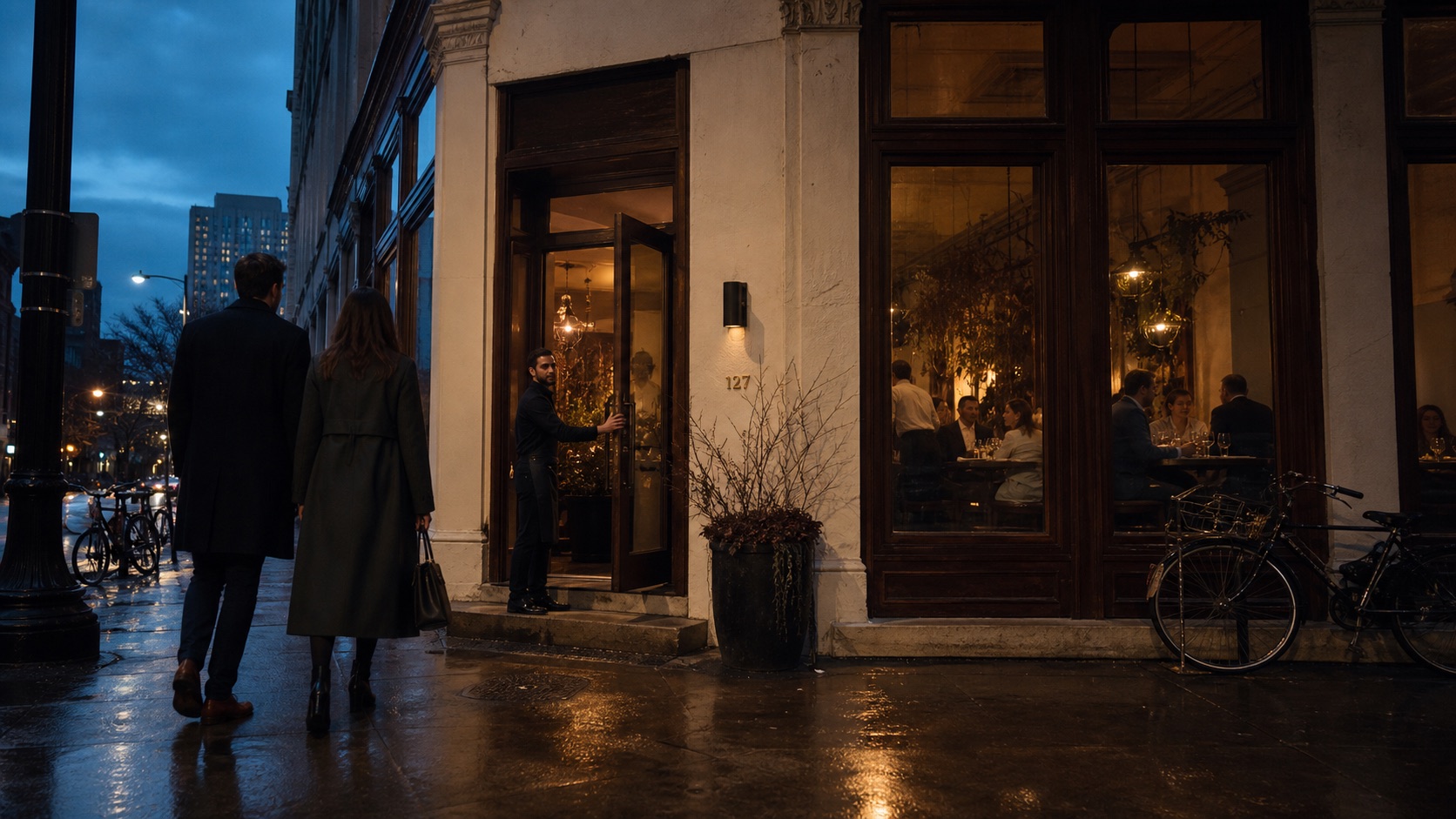 Guests approaching a warmly lit Chicago restaurant at blue hour while the host holds the door